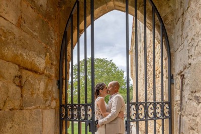 Table dressée avec nappes blanches, verres et seaux à glace, dans une salle en pierre avec de grandes fenêtres.