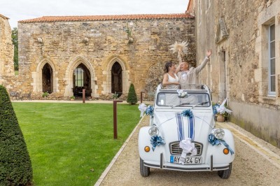 Table dressée avec nappes blanches, verres et seaux à glace, dans une salle en pierre avec de grandes fenêtres.