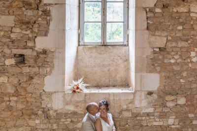 Table dressée avec nappes blanches, verres et seaux à glace, dans une salle en pierre avec de grandes fenêtres.
