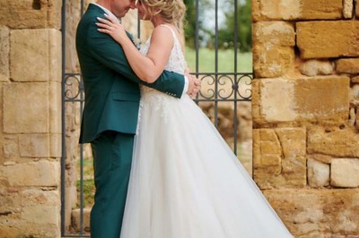 Table dressée avec nappes blanches, verres et seaux à glace, dans une salle en pierre avec de grandes fenêtres.