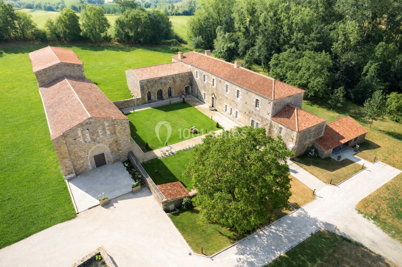 Vue aérienne d'un domaine rural avec bâtiments en pierre, toits en tuiles, cour centrale et espaces verts environnants.