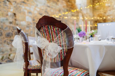 Cour intérieure d'un bâtiment historique en pierre, aménagée avec des tables hautes et éclairée par un soleil éclatant.