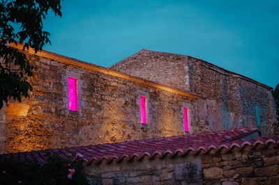 Cour intérieure d'un bâtiment historique en pierre, aménagée avec des tables hautes et éclairée par un soleil éclatant.
