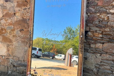 Cour intérieure d'un bâtiment historique en pierre, aménagée avec des tables hautes et éclairée par un soleil éclatant.
