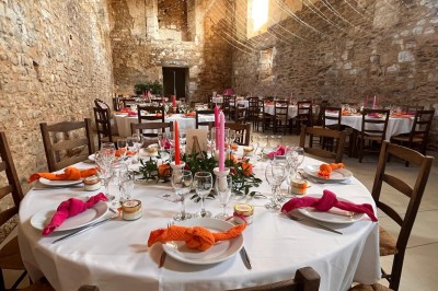 Cour intérieure d'un bâtiment historique en pierre, aménagée avec des tables hautes et éclairée par un soleil éclatant.