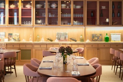 Chambre lumineuse sous combles avec poutres apparentes, lit à baldaquin, table en bois et fenêtre donnant sur l'extérieur.