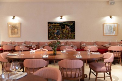 Chambre lumineuse sous combles avec poutres apparentes, lit à baldaquin, table en bois et fenêtre donnant sur l'extérieur.