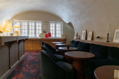 Chambre lumineuse sous combles avec poutres apparentes, lit à baldaquin, table en bois et fenêtre donnant sur l'extérieur.