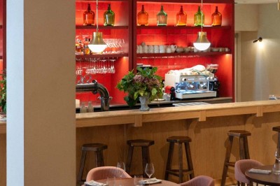 Chambre lumineuse sous combles avec poutres apparentes, lit à baldaquin, table en bois et fenêtre donnant sur l'extérieur.