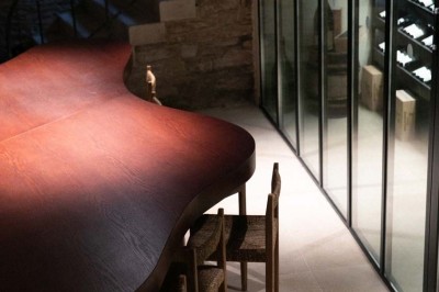 Chambre lumineuse sous combles avec poutres apparentes, lit à baldaquin, table en bois et fenêtre donnant sur l'extérieur.