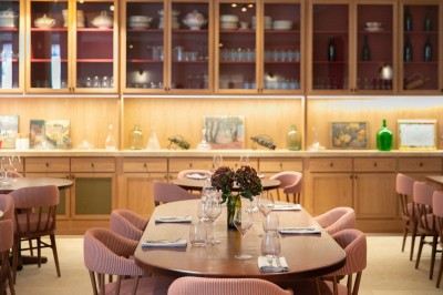 Salle de réunion lumineuse avec une grande table en bois, des fauteuils blancs et des fresques murales représentant des…