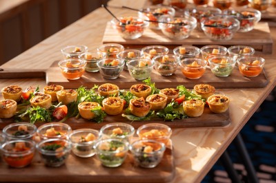 Douche avec carrelage blanc, robinetterie chromée, lavabo avec vase de fleurs séchées et flacon de savon.