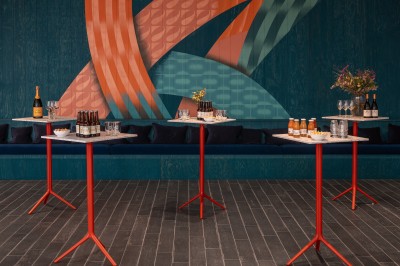 Couloir d'hôtel avec murs roses, moquette bleue à motifs et portes numérotées de chaque côté.