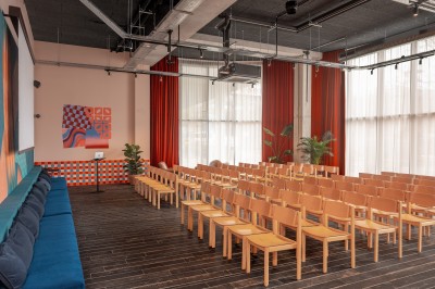 Couloir d'hôtel avec murs roses, moquette bleue à motifs et portes numérotées de chaque côté.