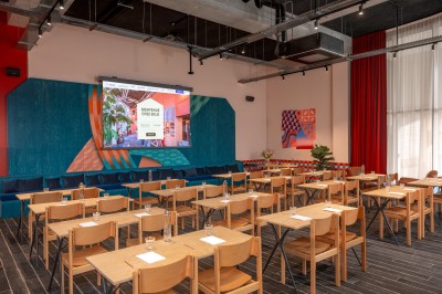 Couloir d'hôtel avec murs roses, moquette bleue à motifs et portes numérotées de chaque côté.