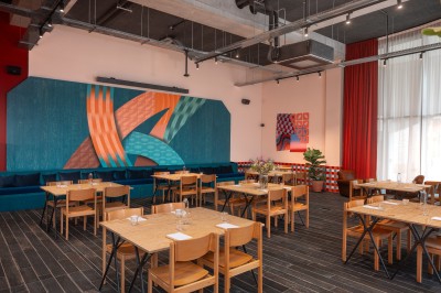 Couloir d'hôtel avec murs roses, moquette bleue à motifs et portes numérotées de chaque côté.