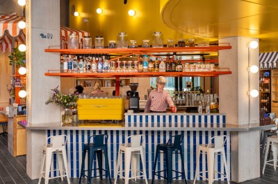 Couloir d'hôtel avec murs roses, moquette bleue à motifs et portes numérotées de chaque côté.
