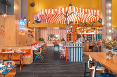 Couloir d'hôtel avec murs roses, moquette bleue à motifs et portes numérotées de chaque côté.