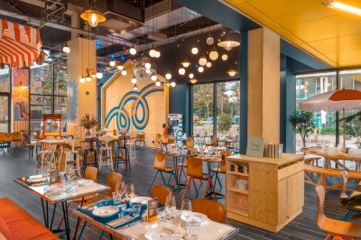 Couloir d'hôtel avec murs roses, moquette bleue à motifs et portes numérotées de chaque côté.