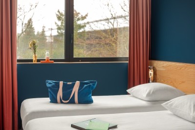 Couloir d'hôtel avec murs roses, moquette bleue à motifs et portes numérotées de chaque côté.