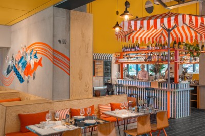 Couloir d'hôtel avec murs roses, moquette bleue à motifs et portes numérotées de chaque côté.