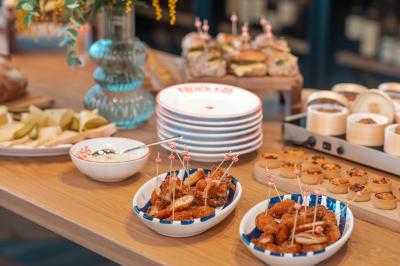 Douche avec carrelage blanc, robinetterie chromée, lavabo avec vase de fleurs séchées et savon.