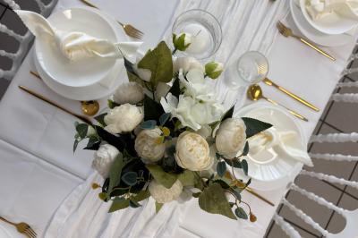 Bougies blanches et roses dans des vases en verre décorent une table recouverte d'une nappe blanche.