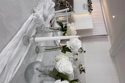 Bougies blanches et roses dans des vases en verre décorent une table recouverte d'une nappe blanche.