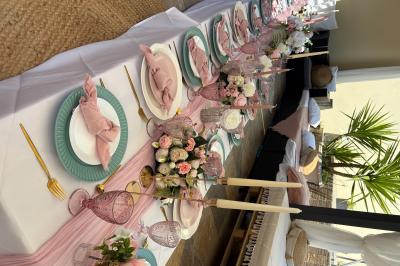 Bougies blanches et roses dans des vases en verre décorent une table recouverte d'une nappe blanche.