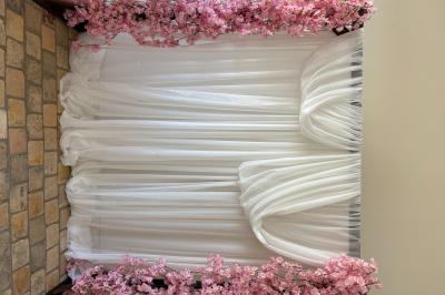 Bougies blanches et roses dans des vases en verre décorent une table recouverte d'une nappe blanche.