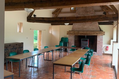 Plusieurs voitures blanches stationnées sur un parking en gravier, entouré de haies et de bâtiments.