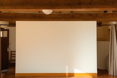 Plusieurs voitures blanches stationnées sur un parking en gravier, entouré de haies et de bâtiments.