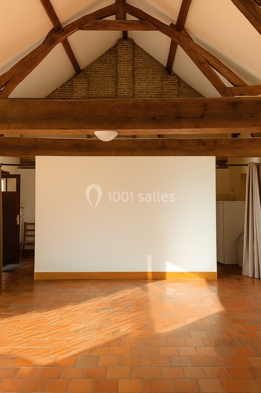 Plafond avec poutres apparentes en bois, mur blanc et sol en carrelage orange dans une pièce lumineuse.