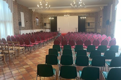 Plusieurs voitures blanches stationnées sur un parking en gravier, entouré de haies et de bâtiments.