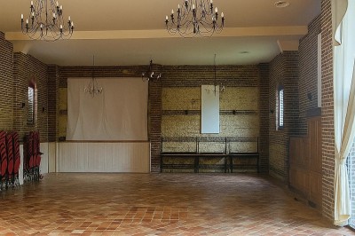 Plusieurs voitures blanches stationnées sur un parking en gravier, entouré de haies et de bâtiments.