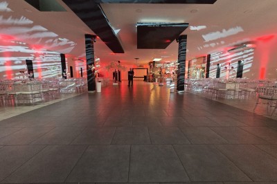 Salle de réception décorée avec des lumières rouges, tables dressées et projection lumineuse au sol.