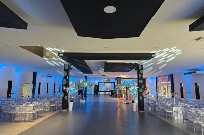 Salle de réception décorée avec des lumières rouges, tables dressées et projection lumineuse au sol.