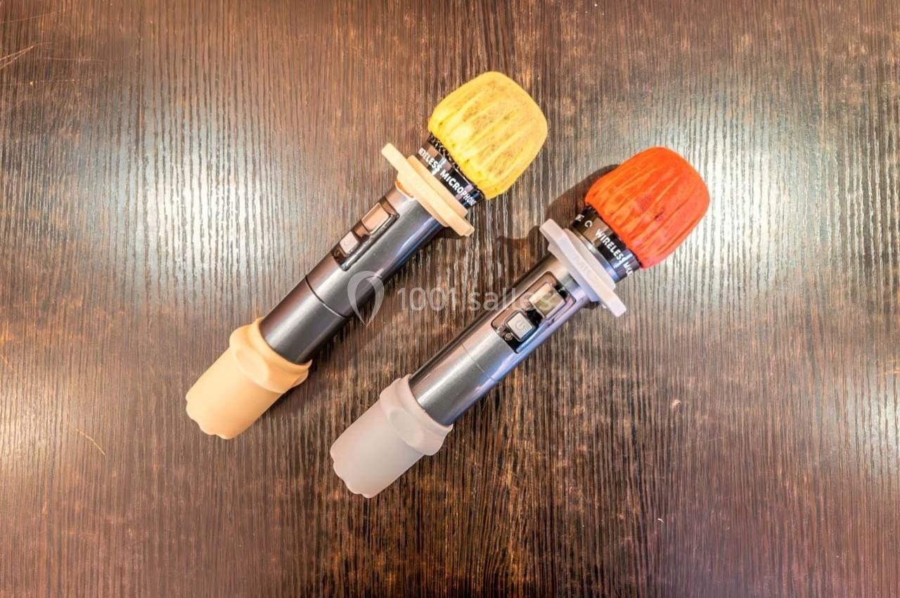 Deux poignées de sabres laser avec embouts colorés jaune et rouge, posées sur une surface en bois sombre.