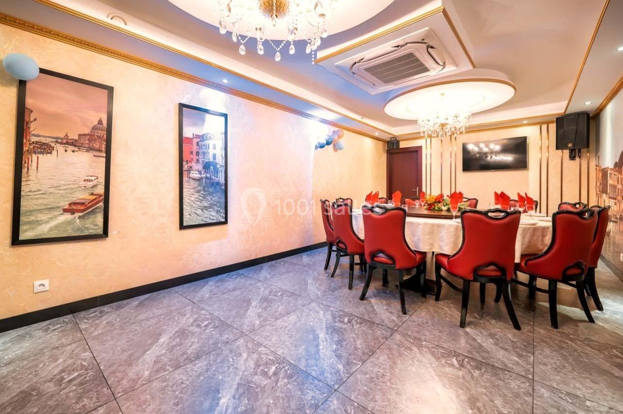 Salle à manger élégante avec table dressée, chaises rouges, lustres et décorations murales représentant des paysages urbains.