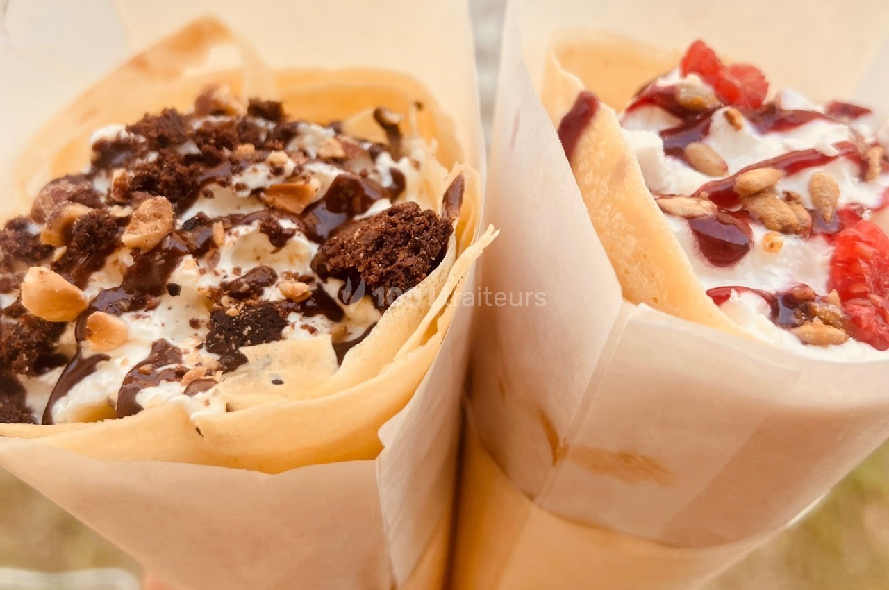 Deux crêpes garnies, l'une avec chocolat et éclats de noisettes, l'autre avec fruits rouges et sauce sucrée.
