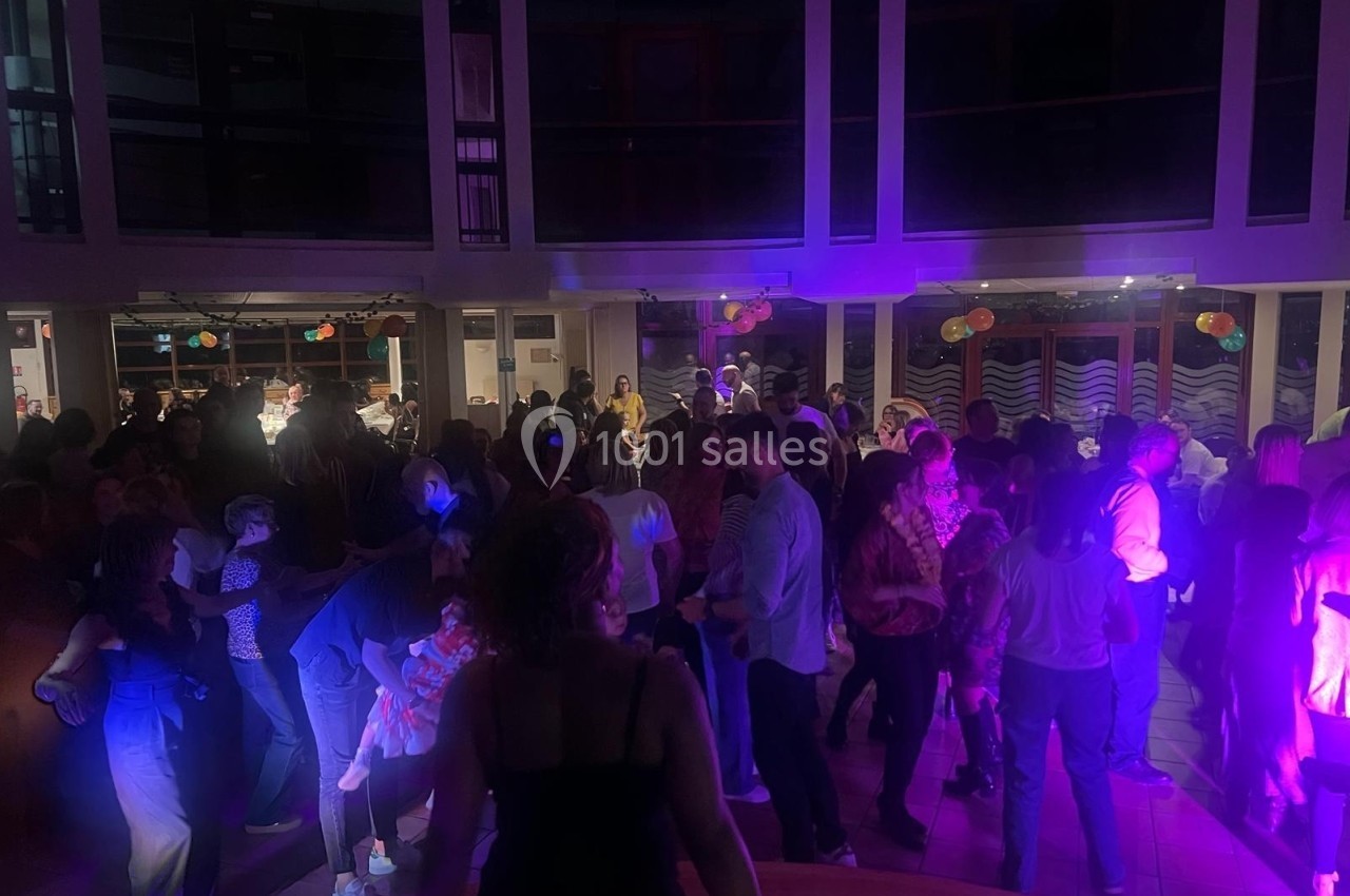 Groupe de personnes dansant dans une salle éclairée par des lumières colorées, ambiance festive en soirée.