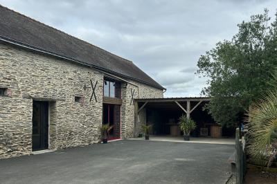 Cuisine professionnelle avec plans de travail en inox, évier, lave-vaisselle industriel et vue sur l'extérieur.