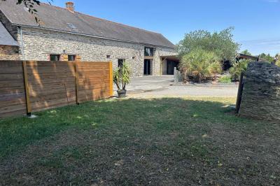 Cuisine professionnelle avec plans de travail en inox, évier, lave-vaisselle industriel et vue sur l'extérieur.