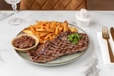 Tartelette aux fraises garnie de fruits frais et de sucre glace, servie sur une assiette verte avec une cuillère dorée.