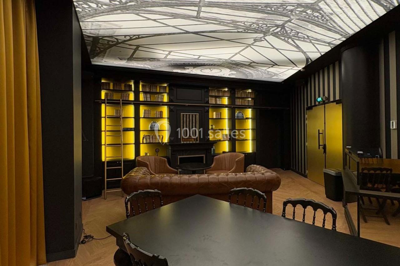 Salle élégante avec canapé en cuir, étagères éclairées, table noire et plafond décoré d'un motif architectural.