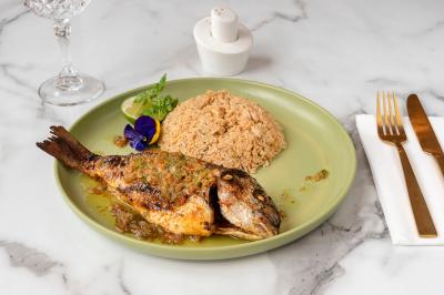 Salle de réunion avec une grande table en bois, entourée de fauteuils rembourrés, éclairée par une lampe et une fenêtre.