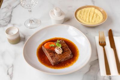 Salle de réunion avec une grande table en bois, entourée de fauteuils rembourrés, éclairée par une lampe et une fenêtre.