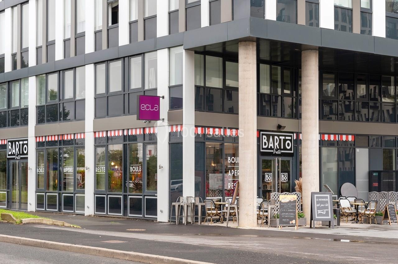 Façade d'un restaurant avec terrasse extérieure, situé au rez-de-chaussée d'un immeuble moderne.