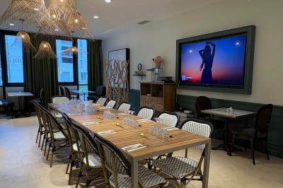 Salle de réunion avec une grande table en bois, entourée de fauteuils rembourrés, éclairée par une lampe et une fenêtre.
