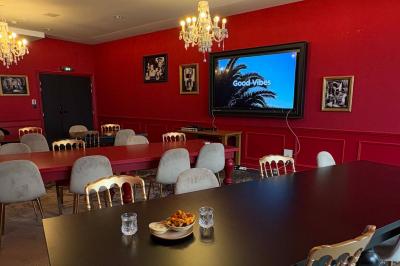 Salle de réunion avec une grande table en bois, entourée de fauteuils rembourrés, éclairée par une lampe et une fenêtre.